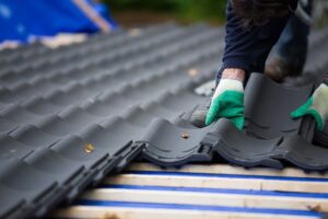 Worker in gloves installing commercial black roof tiles