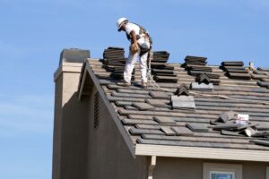 Construction worker in safety harness working on a residential tiled roof.