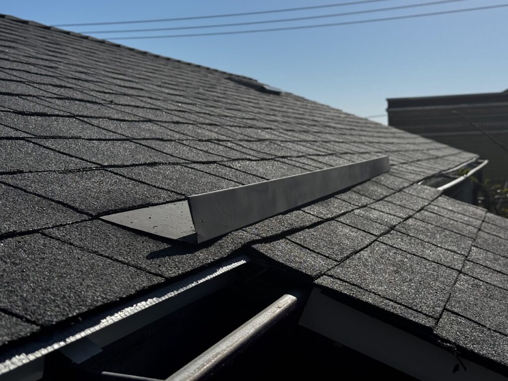 Close-up of sloped asphalt shingle roof with metal ridge cap