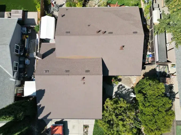 Aerial view of a newly installed brown asphalt shingle roof on a residential home