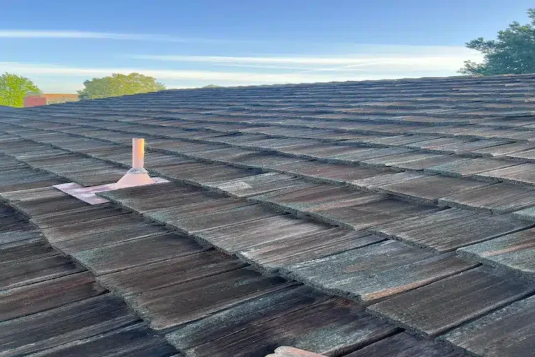 Worn wooden shake roof with visible discoloration and surface damage prior to replacement