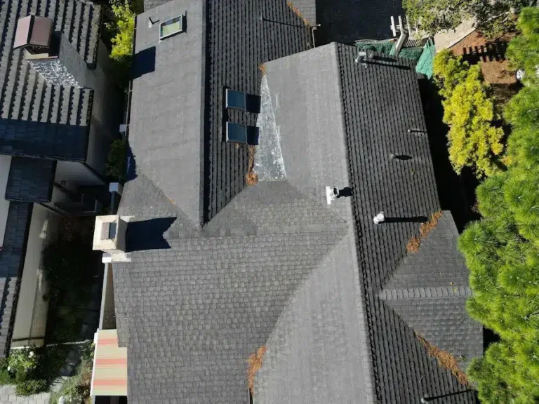 Aging shingle roof with visible wear, skylights, and solar panels