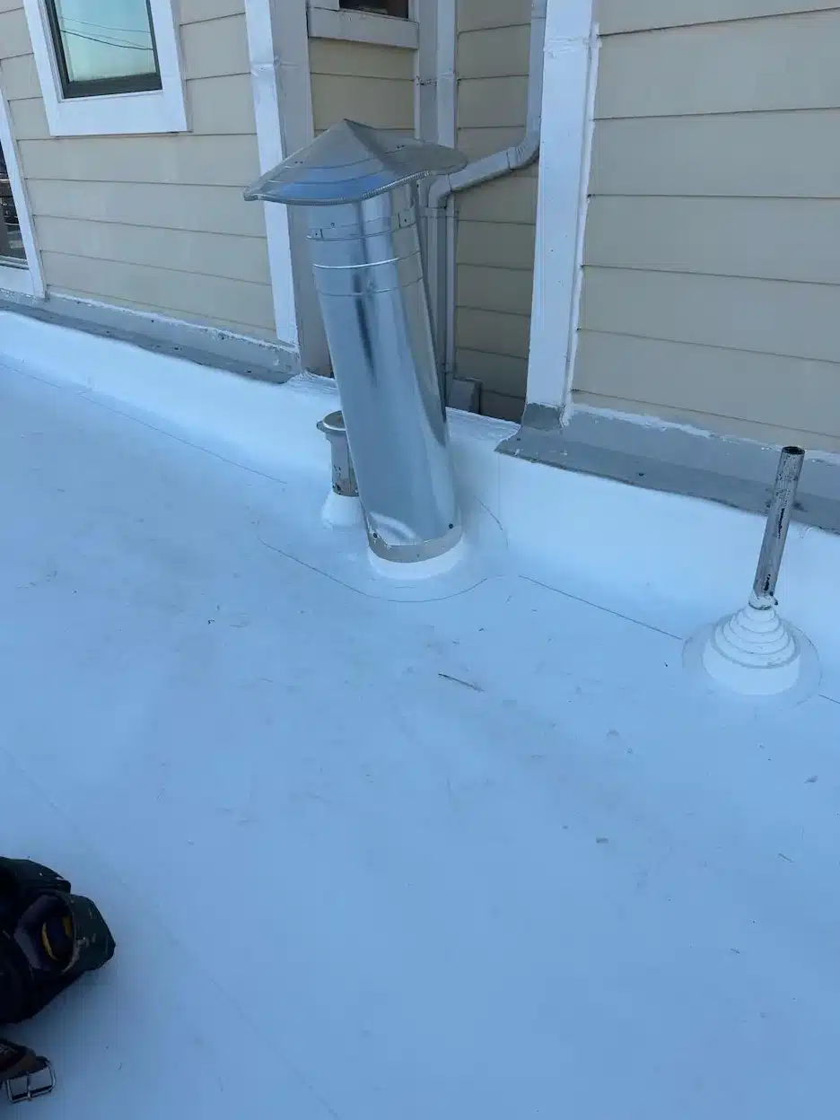 Welded TPO flashing details around furnace flue and vent pipes at the wall transition in San Francisco