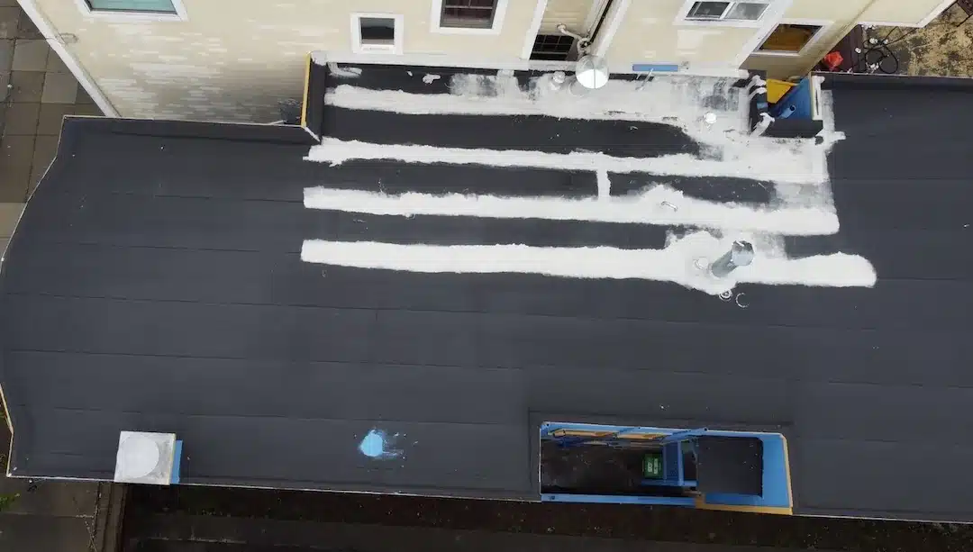 Aerial view of failing flat 3-ply roof with white mastic patch repairs before TPO overlay at 1582 Quesada Ave San Francisco