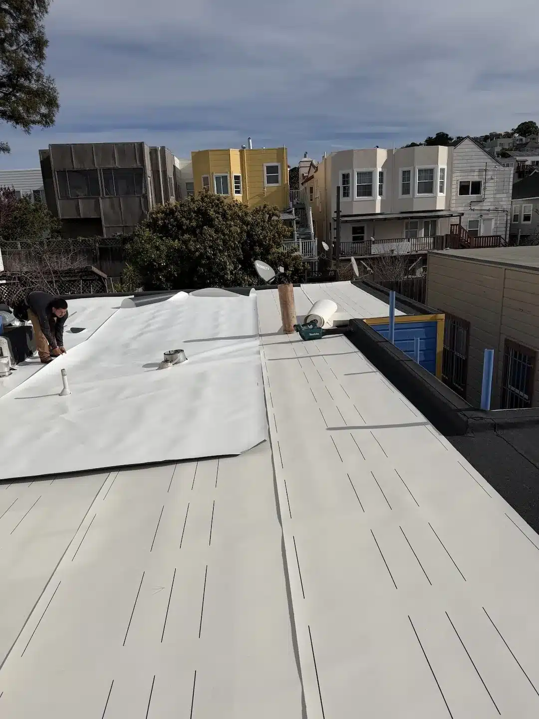 Positioning and aligning TPO membrane sheets during the flat roof overlay installation in San Francisco Bayview