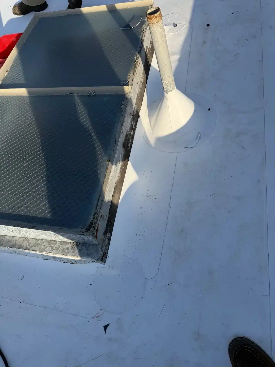 Roofer heat-welding a new white TPO pipe boot and skylight flashing during the San Francisco flat roof overlay