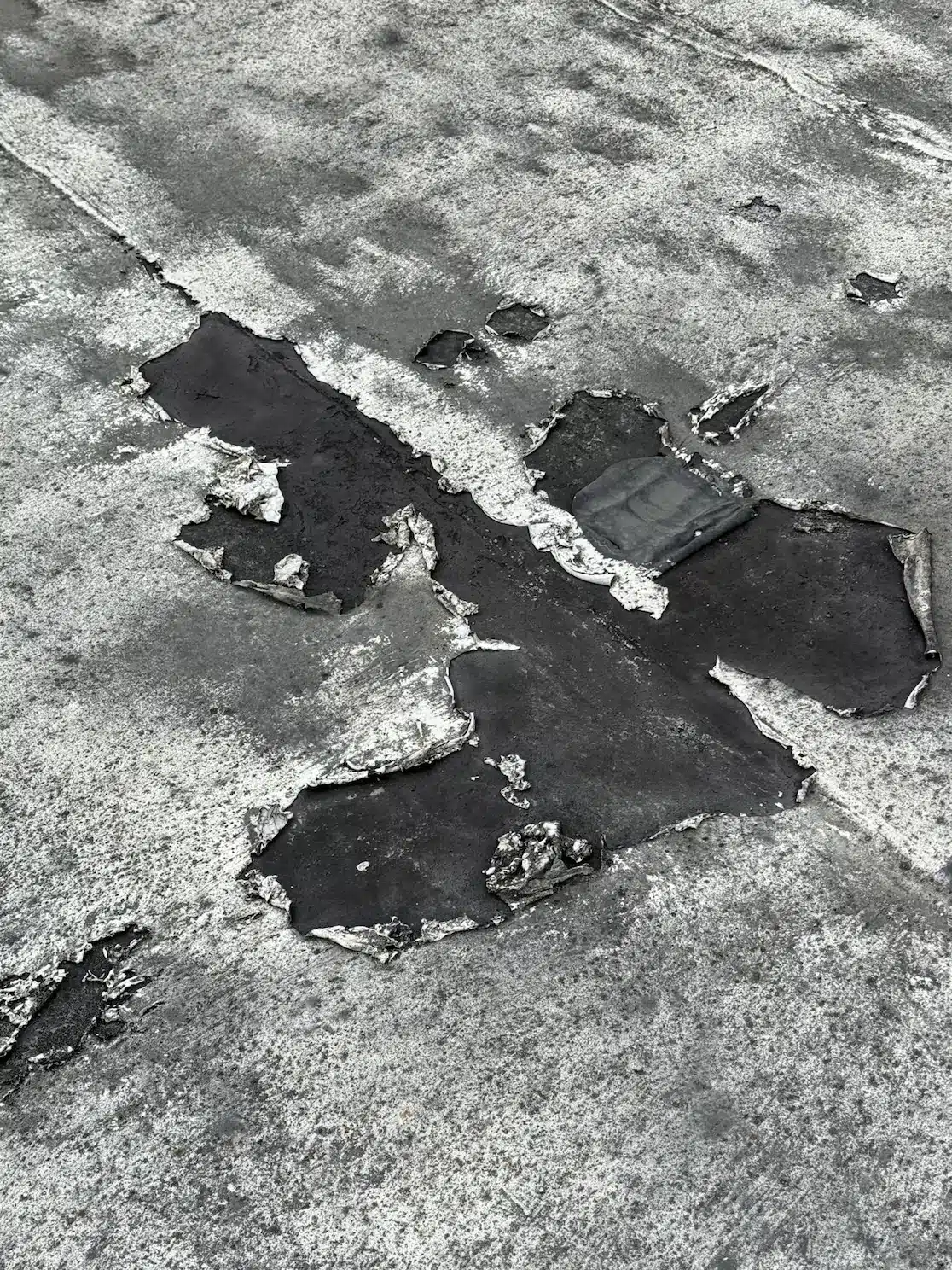 Failing reflective roof coating peeling and delaminating off the old flat roof before TPO overlay at 2219 26th Avenue, San Francisco CA