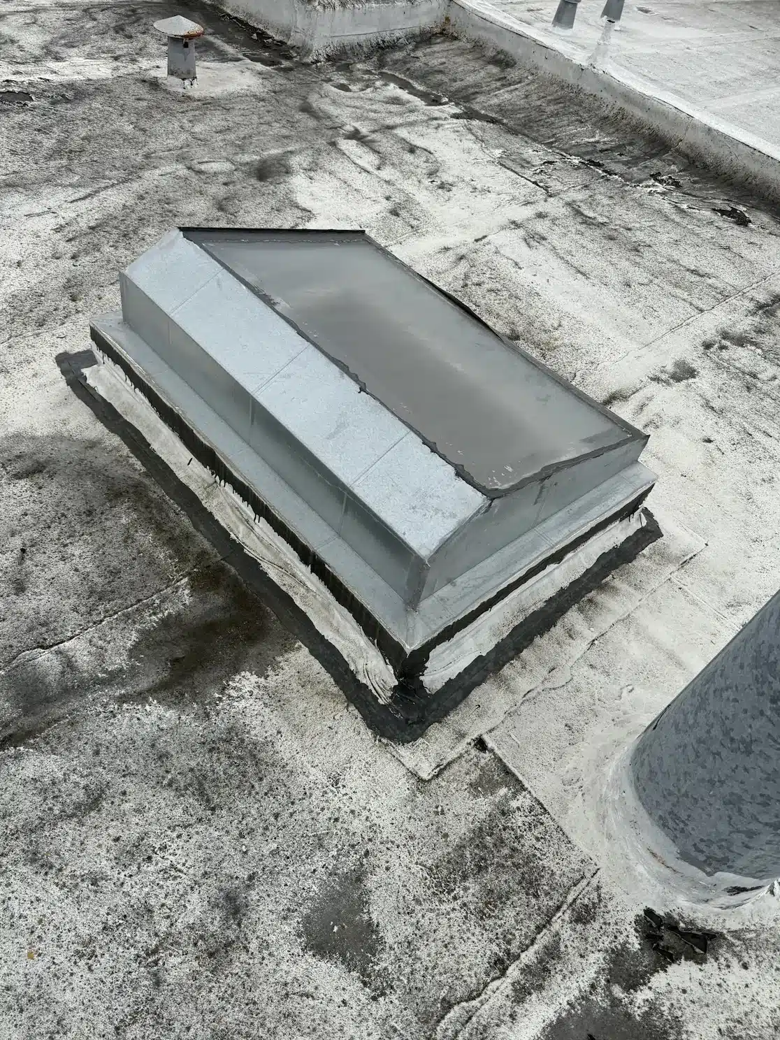 Weathered, patched flat roof and aging skylight curb before the TPO overlay in San Francisco's Sunset District