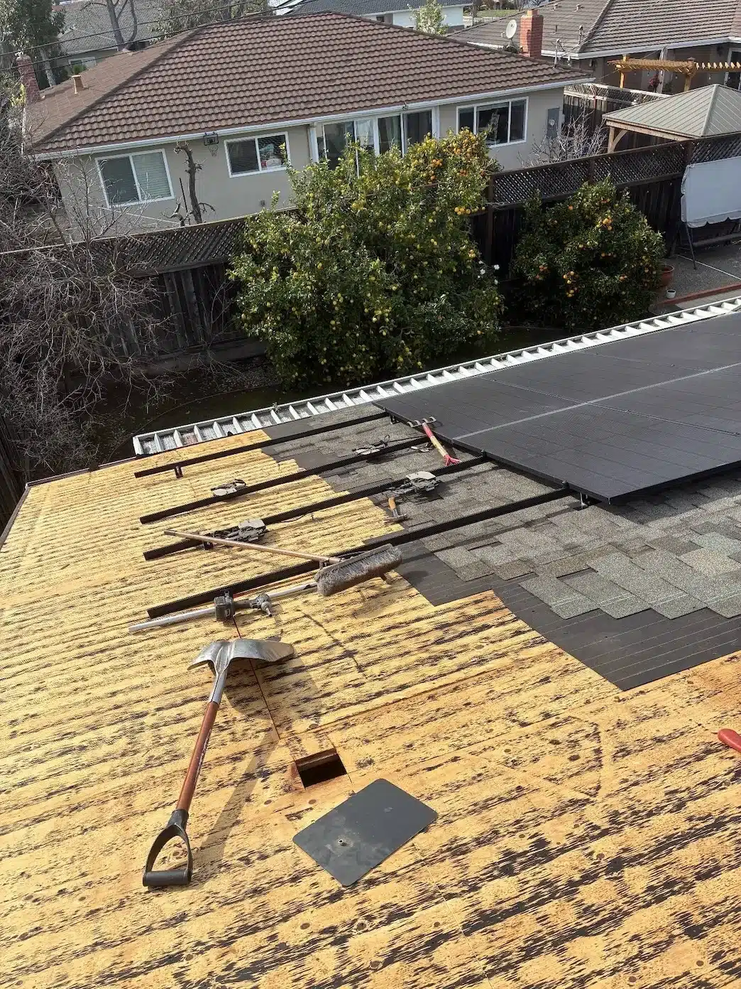 Roof section stripped to the plywood deck during roof repair under solar panels in San Jose
