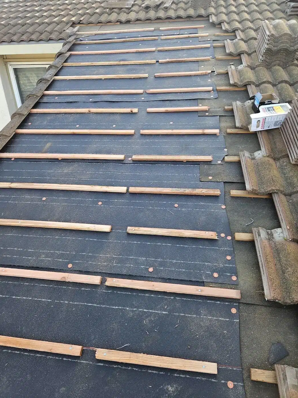Concrete tiles lifted and set aside with new underlayment and wood battens installed during tile reset in Fremont CA