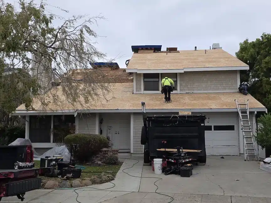 Re-roof in progress with new plywood decking and crew on site at a Foster City home