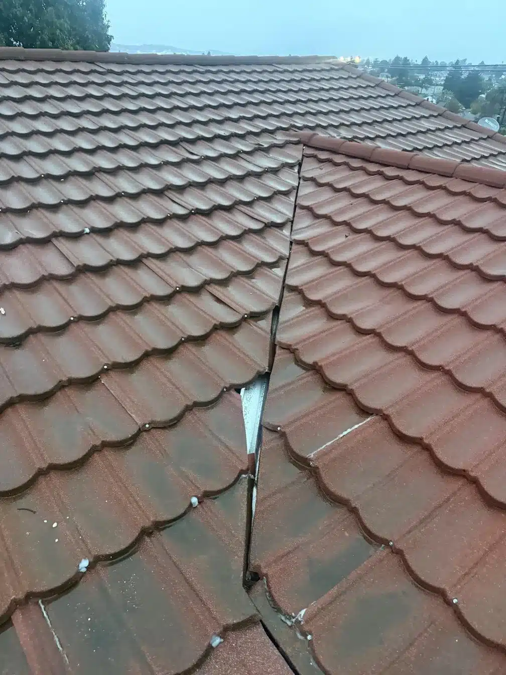 Rain-soaked tile roof junction where two planes meet, documented during leak diagnosis in Richmond