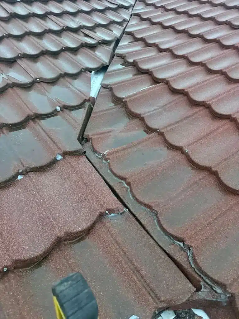 Close-up of failed old sealant and gaps at a tile roof junction before leak repair in Richmond