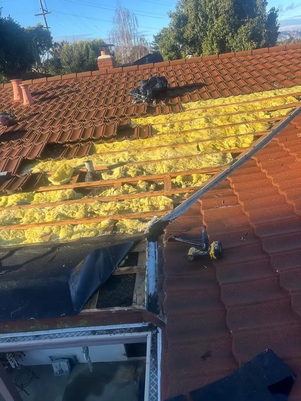 Tile roof opened above the front entry with battens and insulation exposed during urgent leak repair in Richmond