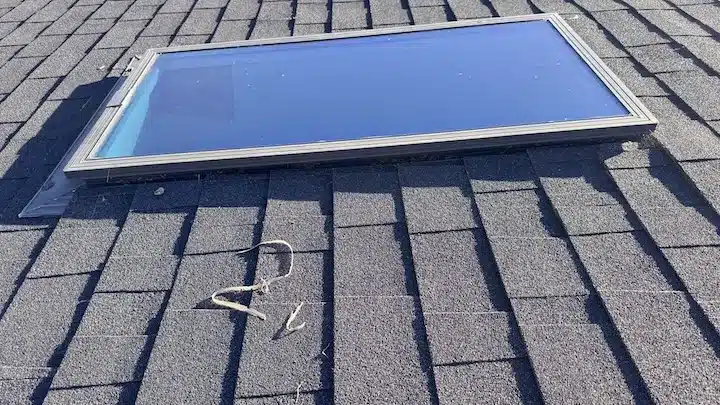 The removed nine-year-old skylight unit on the roof with brittle sealant beads left on the shingles, Sunnyvale CA