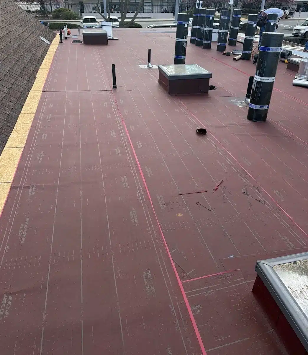 Base sheet installed over new sheathing with torch-applied modified bitumen cap sheet rolls staged, Sunnyvale CA