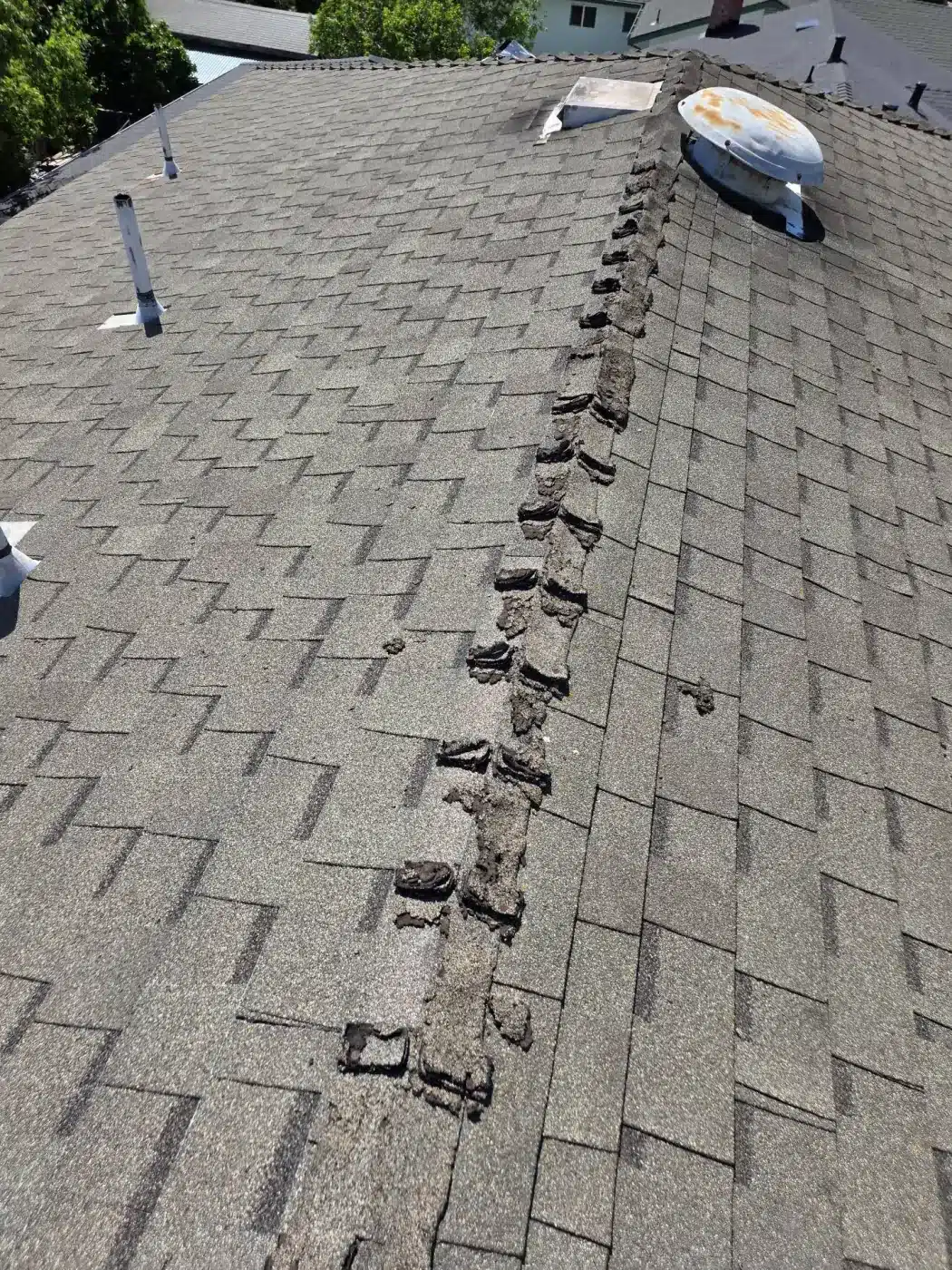 Failed hip and ridge shingle caps and a rusted turbine vent on the old roof in Milpitas, CA