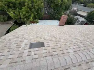 New asphalt shingle roof with a brick chimney and a new attic vent installed near the ridge