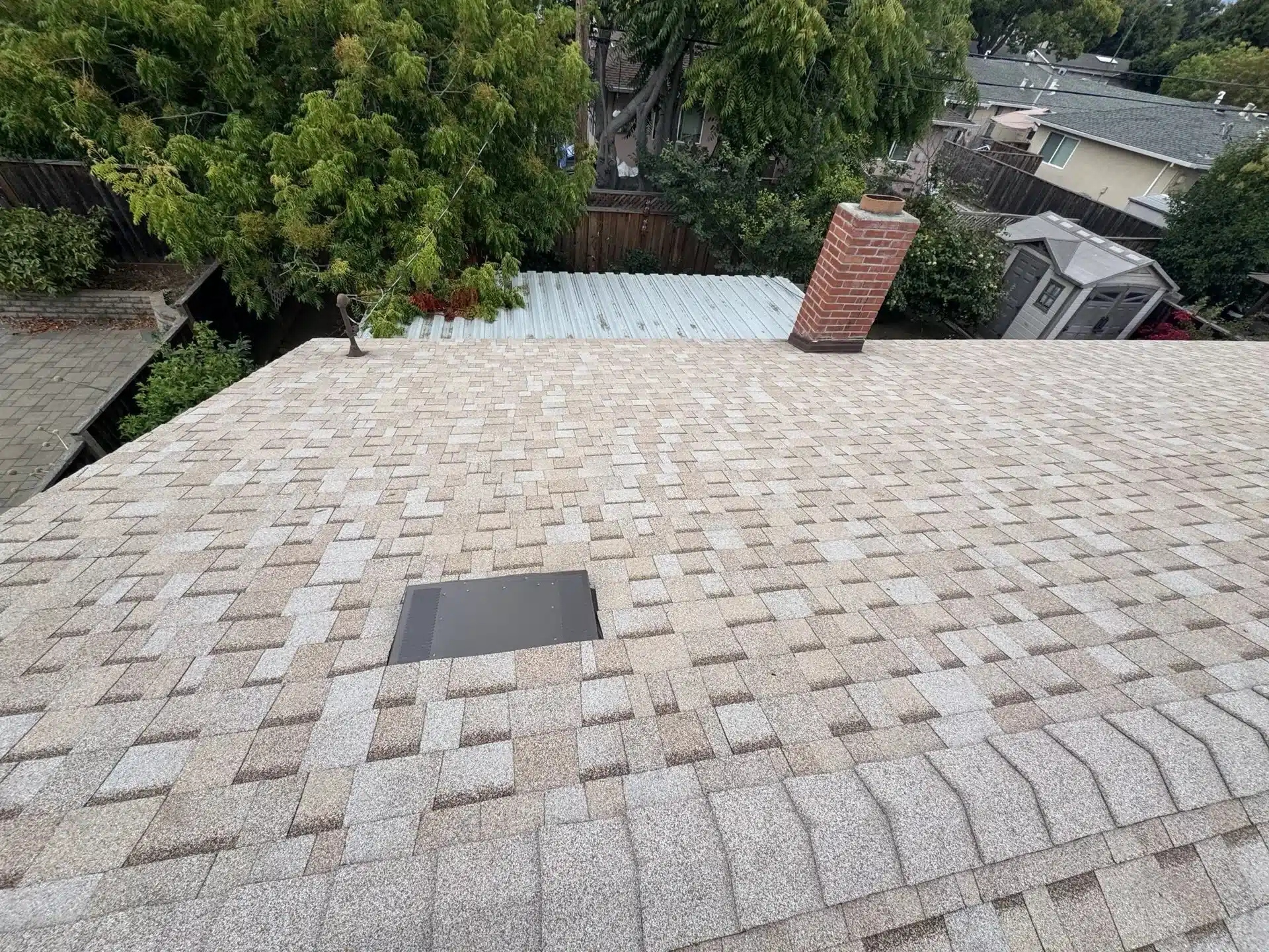 New asphalt shingle roof with fresh flashing at the brick chimney and a low-profile attic vent
