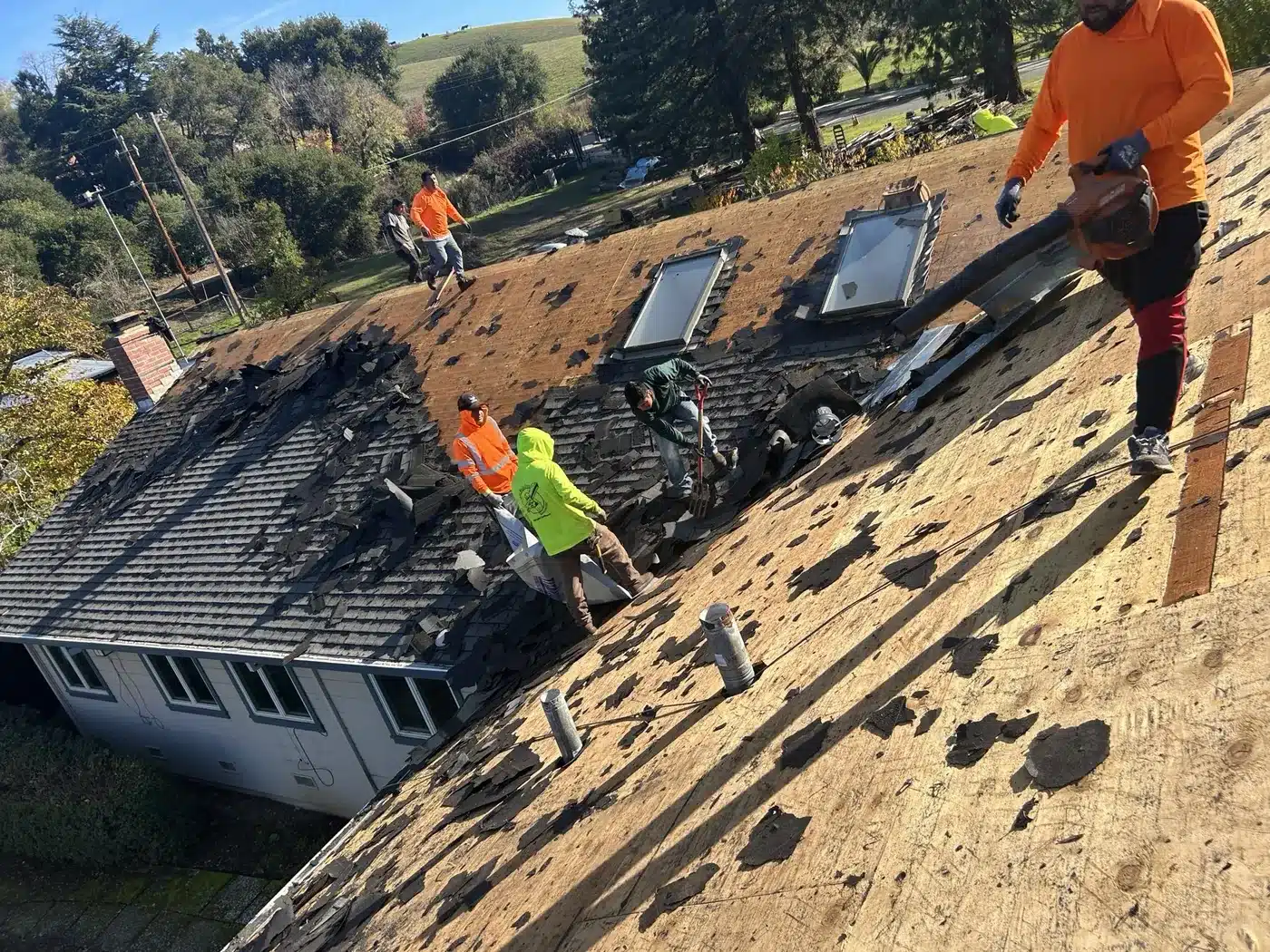 Lifetime Roofing crew tearing off old shingles around skylights in Castro Valley
