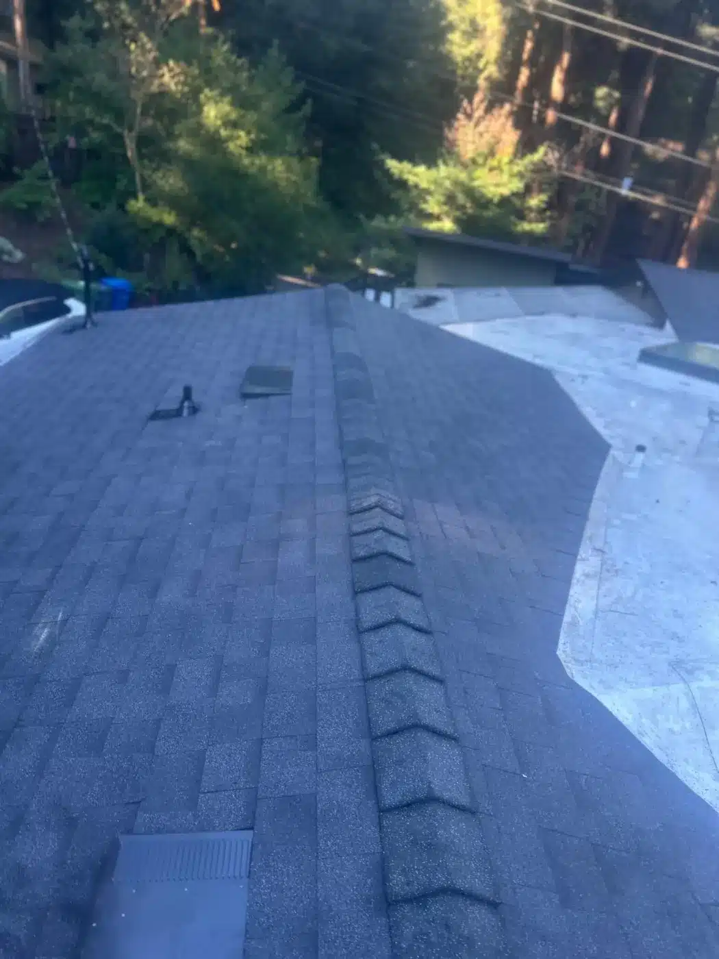 Ridge of a new dark shingle roof after replacement in Felton, CA
