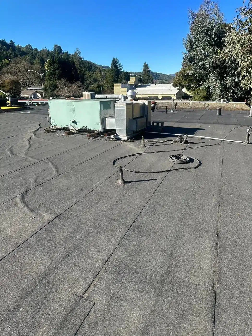 Worn flat torch-down roof with rooftop HVAC before replacement on 4th Street in San Rafael