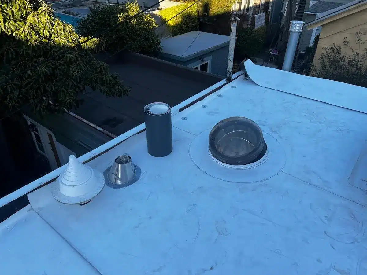 New white flat roof membrane with updated vents and skylight dome on a San Francisco home