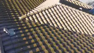 Concrete tile roof on a Morgan Hill home before work, with heavy moss on the shaded planes and clean tan tile on the sun-facing hip
