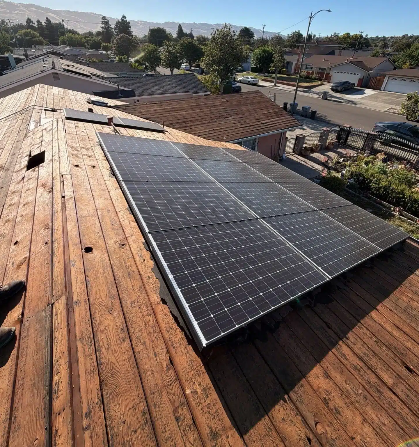 San Jose roof stripped to its original spaced plank sheathing, with the solar array still mounted above it