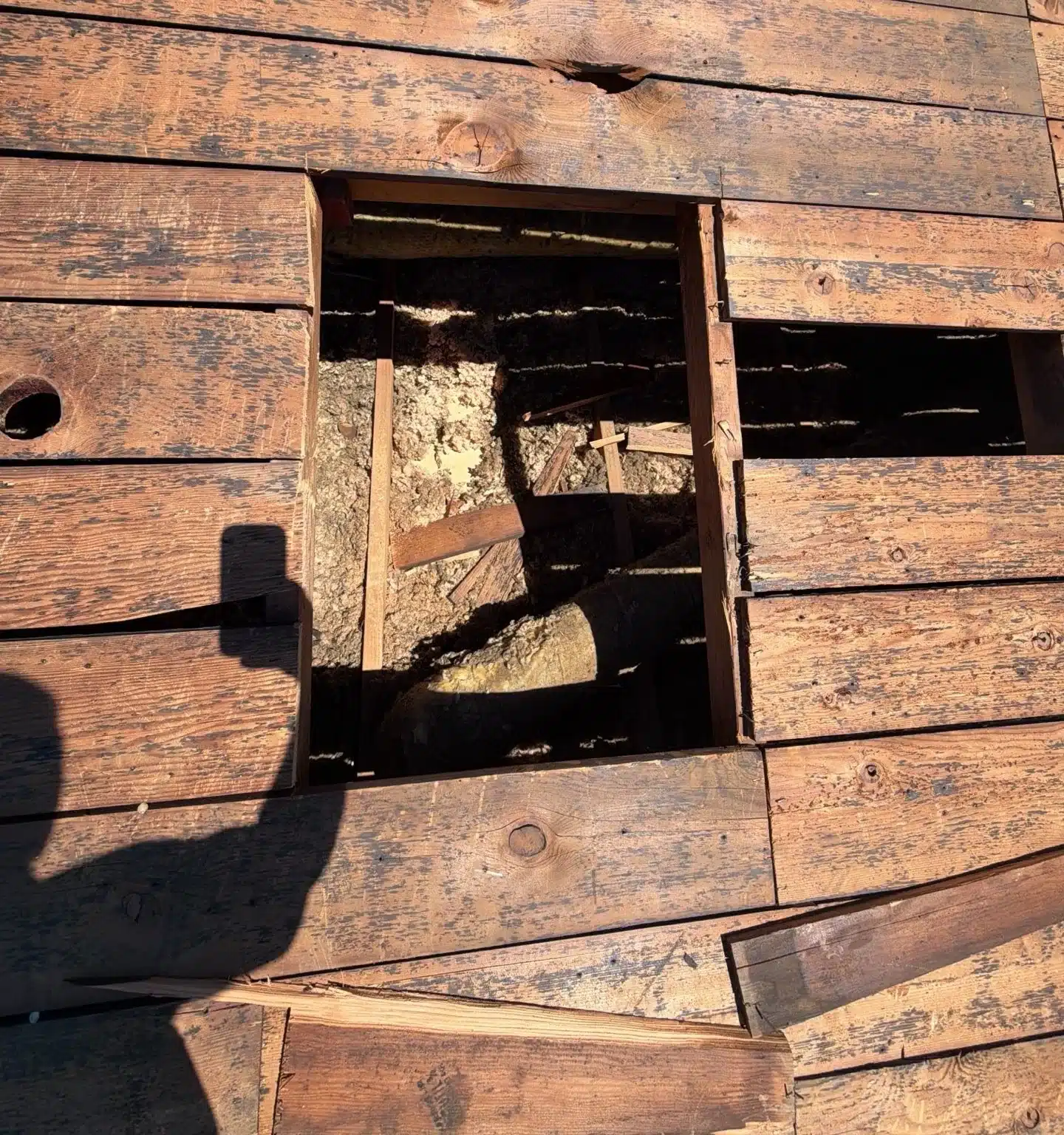 A section cut out of the spaced plank deck on a San Jose roof, exposing the framing below