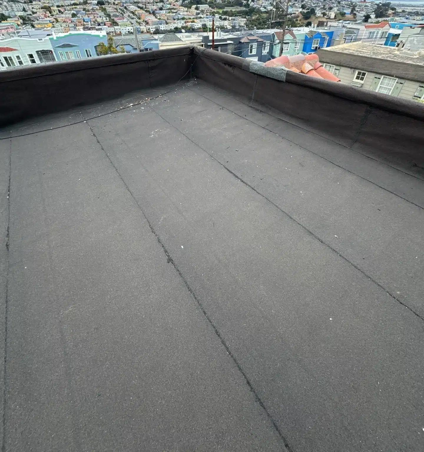 Worn granulated cap sheet across a low-slope roof before replacement in San Francisco