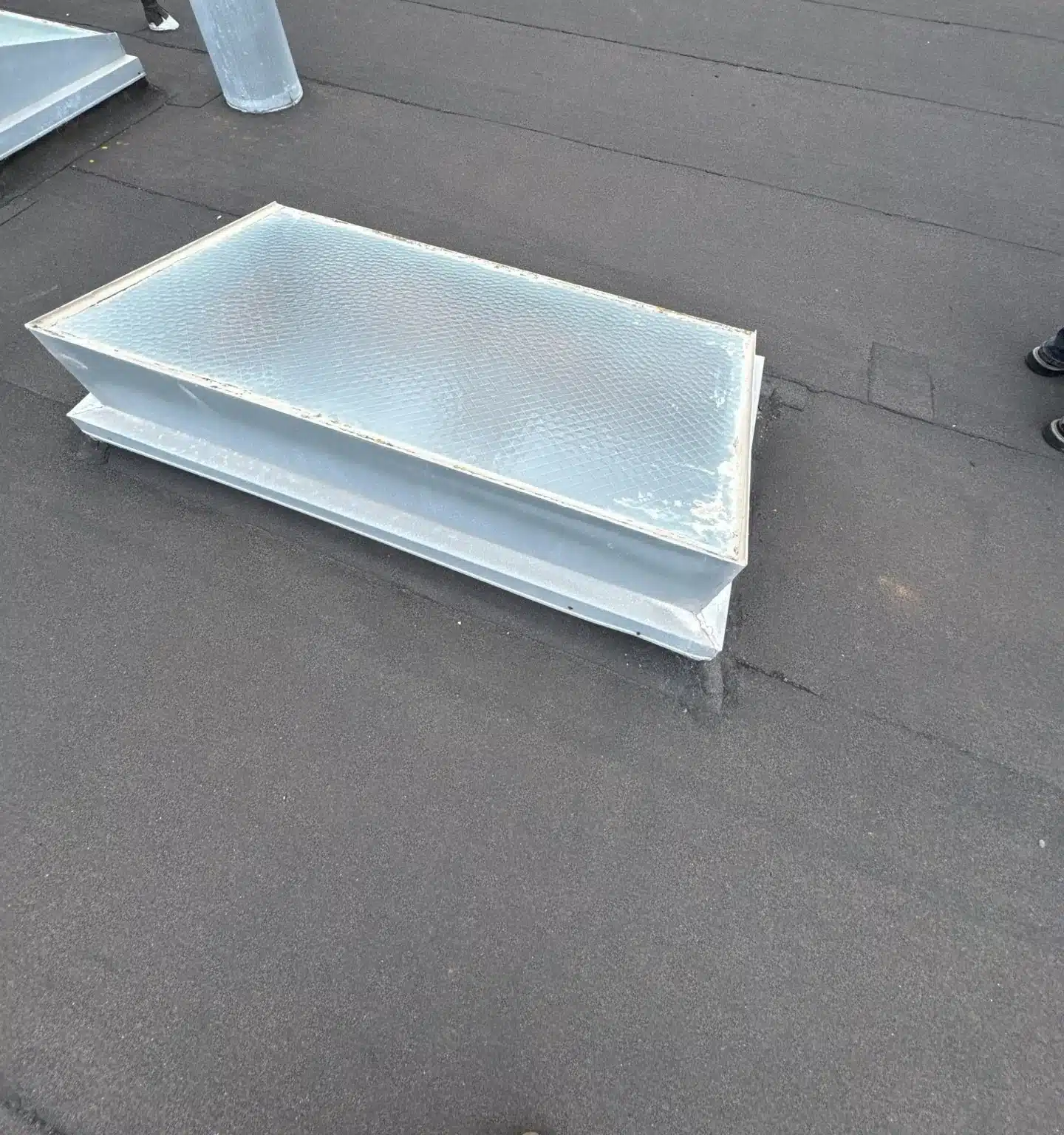Old flat wired-glass skylight with a weathered frame on a San Francisco low-slope roof