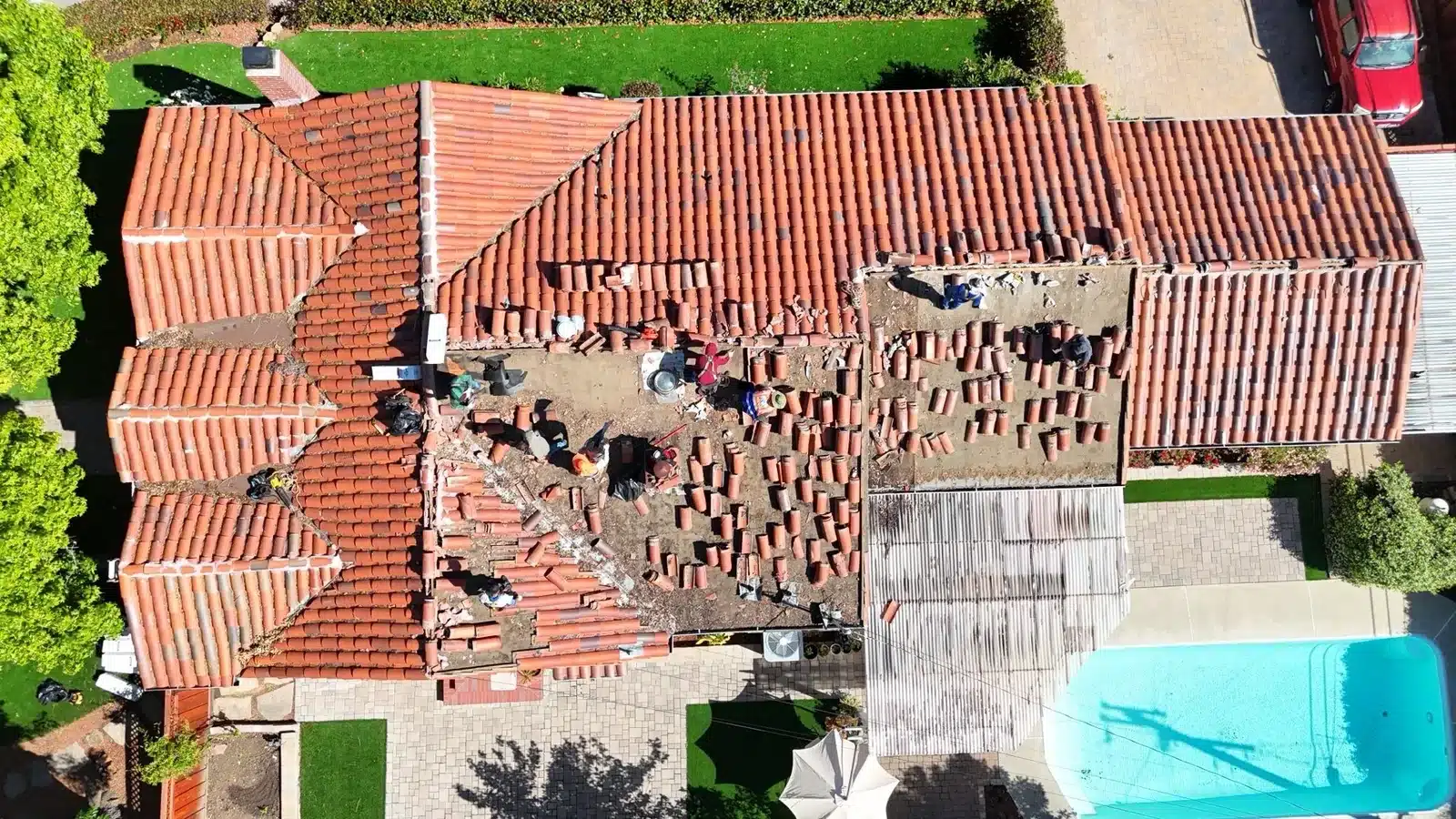 Half the roof stripped to bare boards with salvaged tile stacked alongside the still-tiled section at 1402 Clarita Avenue, San Jose CA