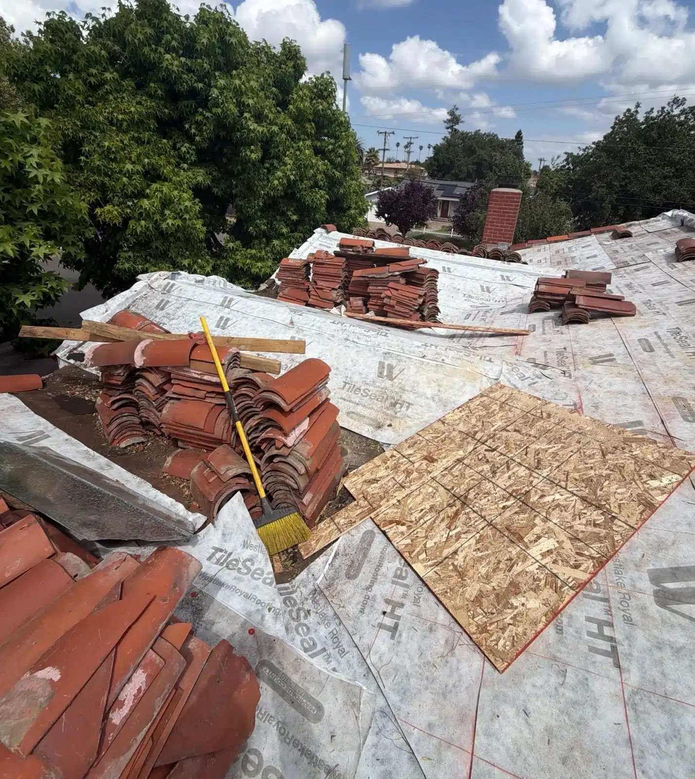 Clay barrel tiles lifted and stacked on the roof with the aged underlayment exposed at 1402 Clarita Avenue, San Jose CA