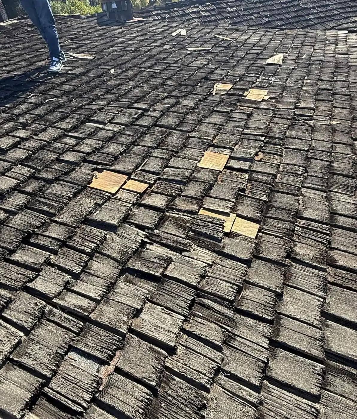 Split and slipped cedar shakes with sheet metal patches on an old wood shake roof in Saratoga, CA