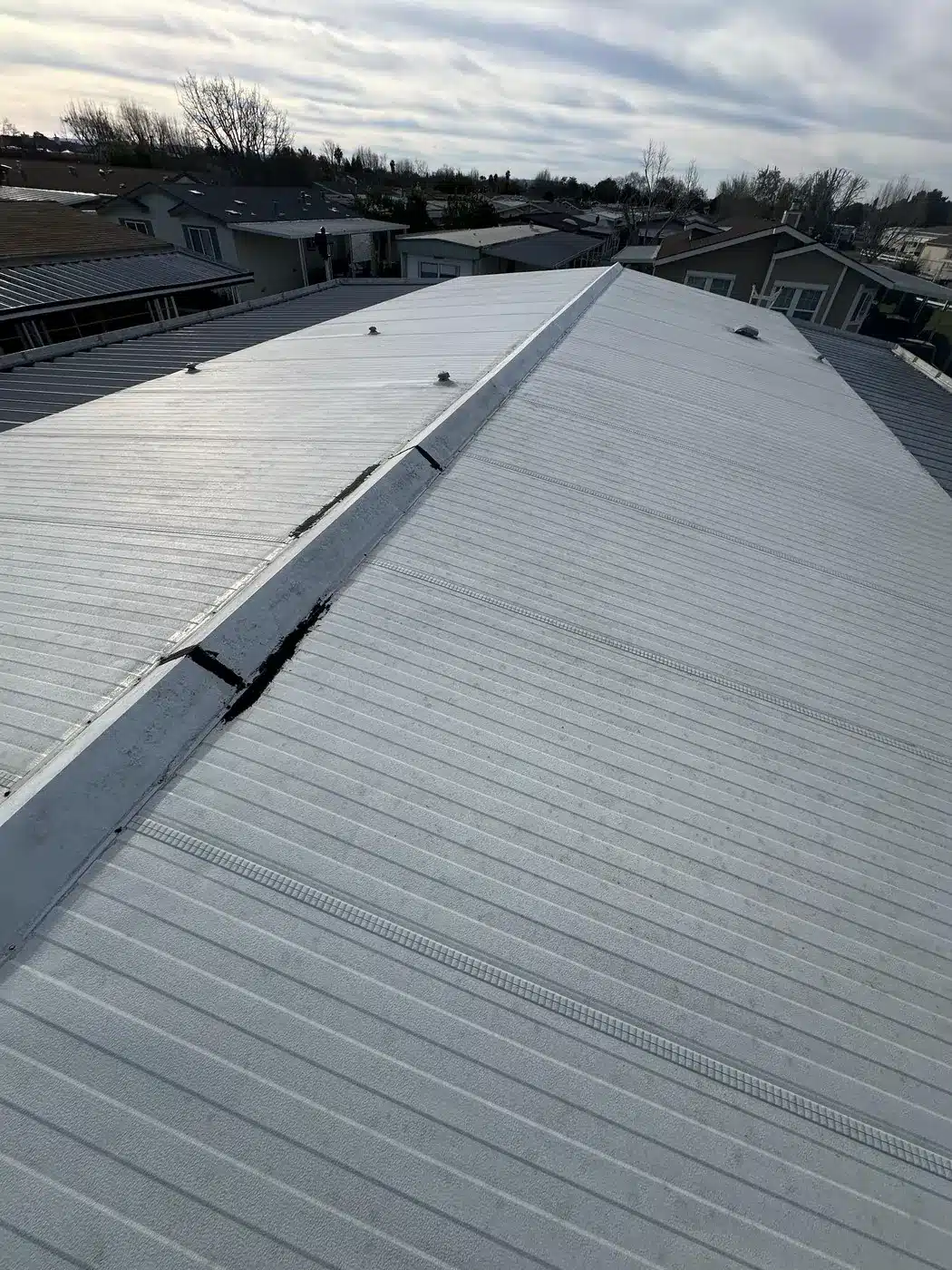 Aging metal manufactured-home roof with sealed ridge cracks before roof-over on Berkeley Road in Hayward