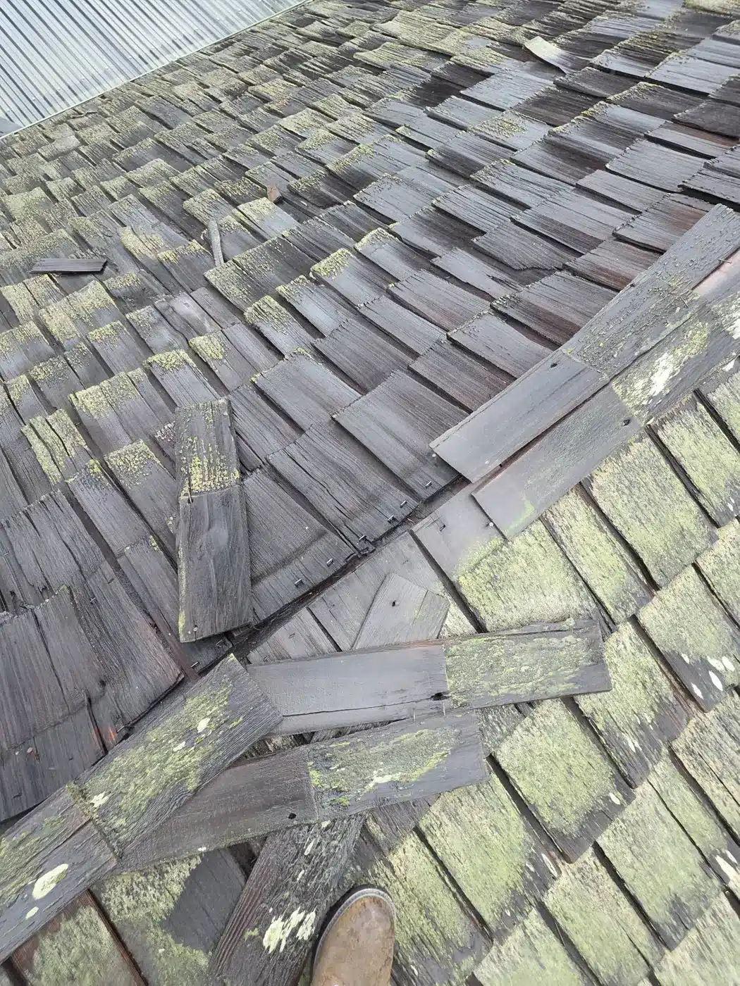Slipped cedar shakes and old patch repairs on a failing wood shake roof in Palo Alto, CA