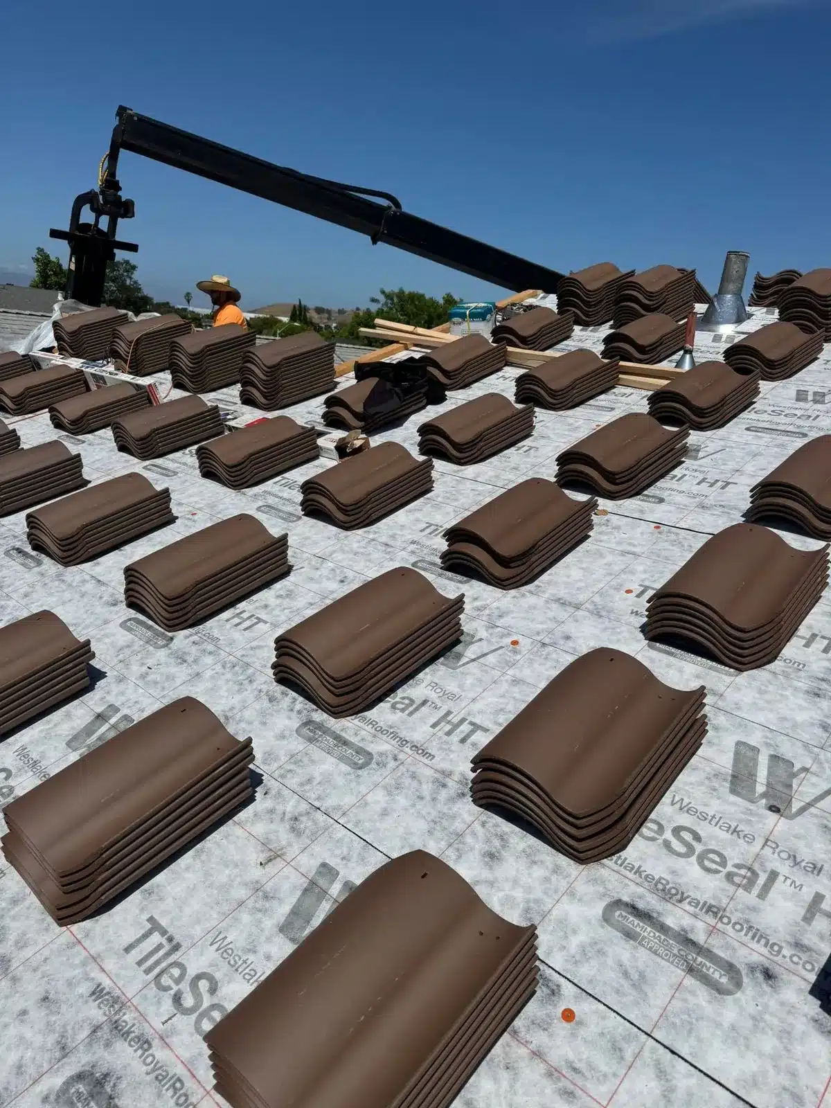 Bundles of concrete tile staged across the underlayment during roof installation