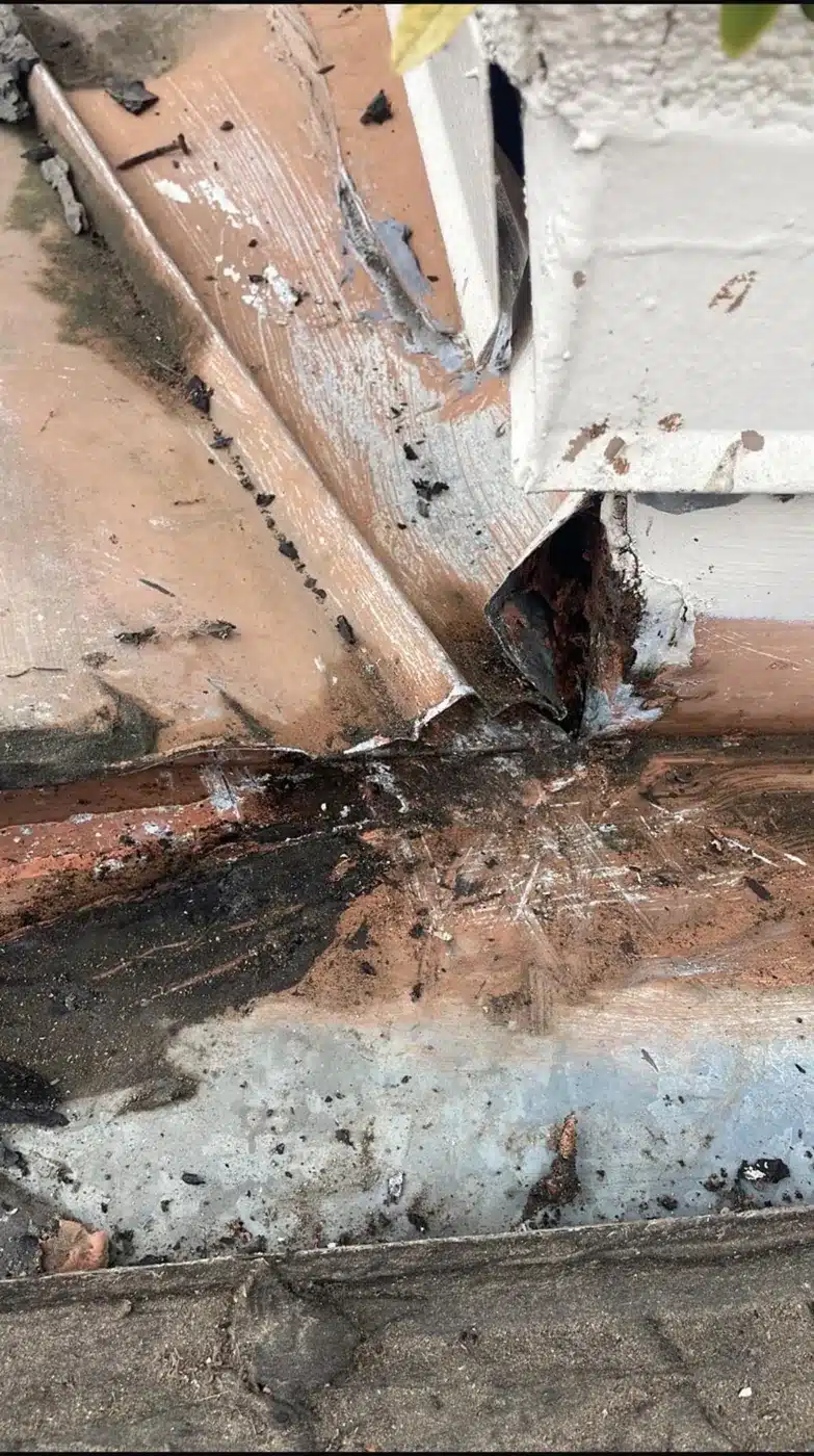 Corroded wall flashing and stained wood at the leak point on a Benicia clay tile roof