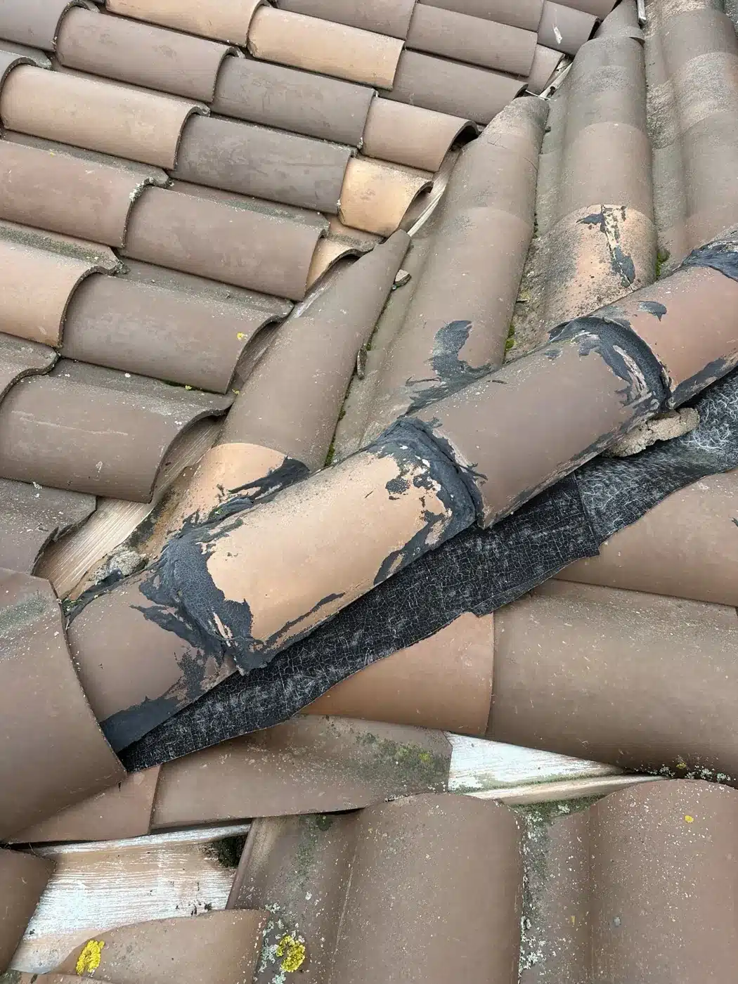 Clay hip tiles smeared with black mastic from earlier patch repairs in Benicia