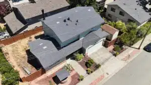 Two-storey house on Proctor Road, Castro Valley CA with its new dark grey architectural shingle roof, seen from above the street