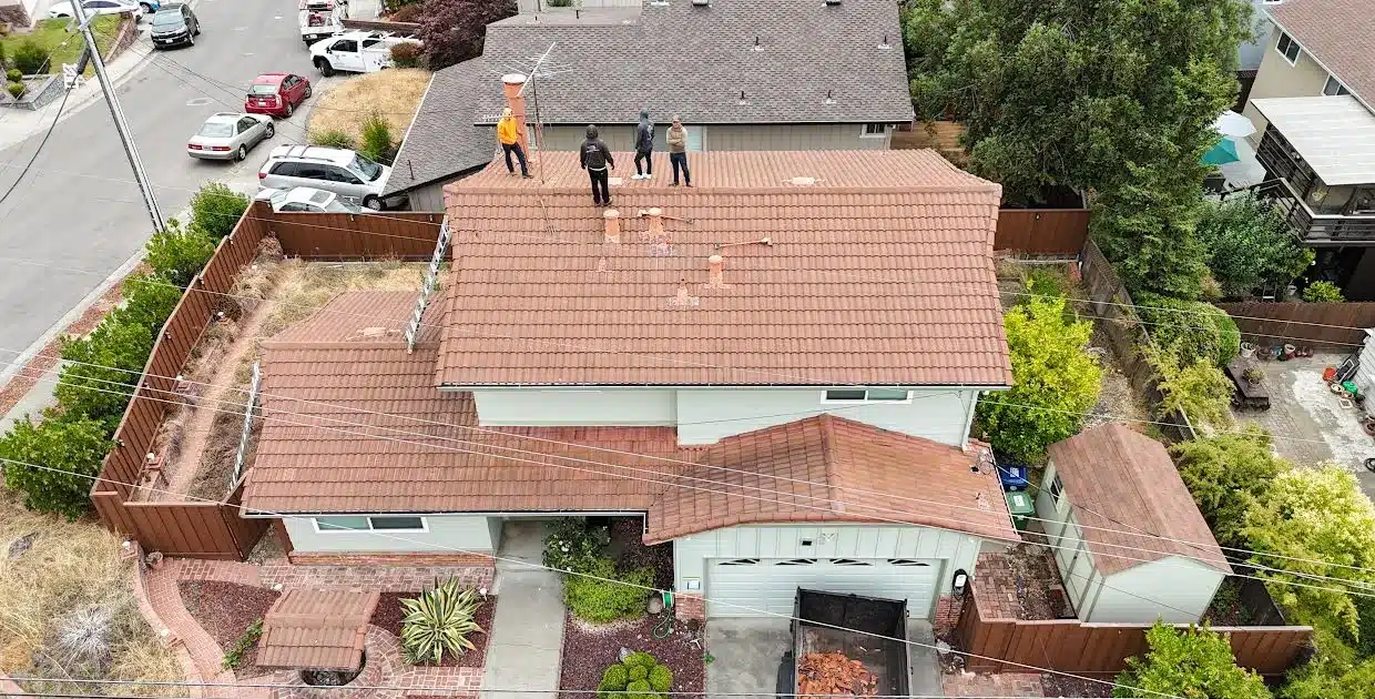 Brown concrete tile roof on a two-storey house on Proctor Road, Castro Valley CA, with the crew on the ridge at the start of the job