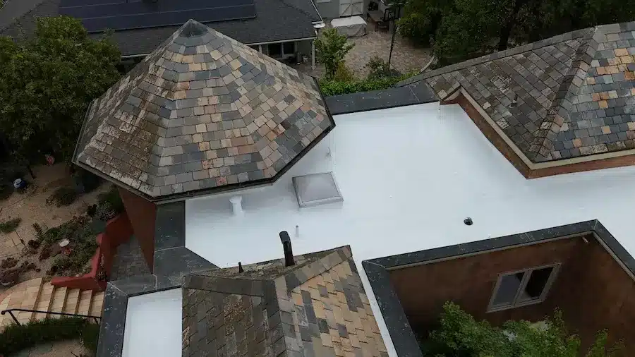 Completed white TPO single-ply membrane roof overlay in Menlo Park with resealed penetrations and repaired slate surround