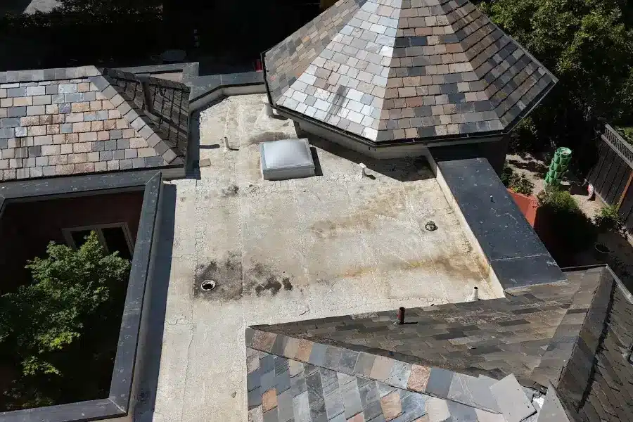 Aged flat TPO roof in Menlo Park with heavy staining, water ponding, and loose slate tiles before restoration