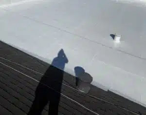 White silicone overlay reflecting sunlight on the low-slope section of a commercial roof in Rodeo CA