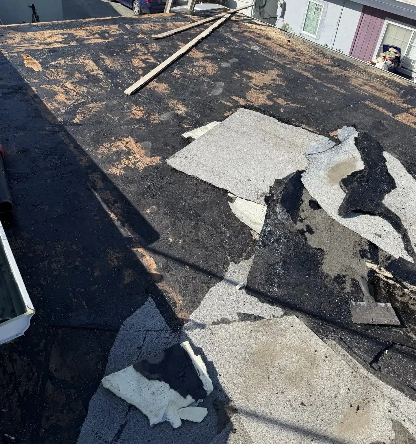 Torn roofing membrane and debris across the deck of an auto shop roof in Rodeo CA before reroofing