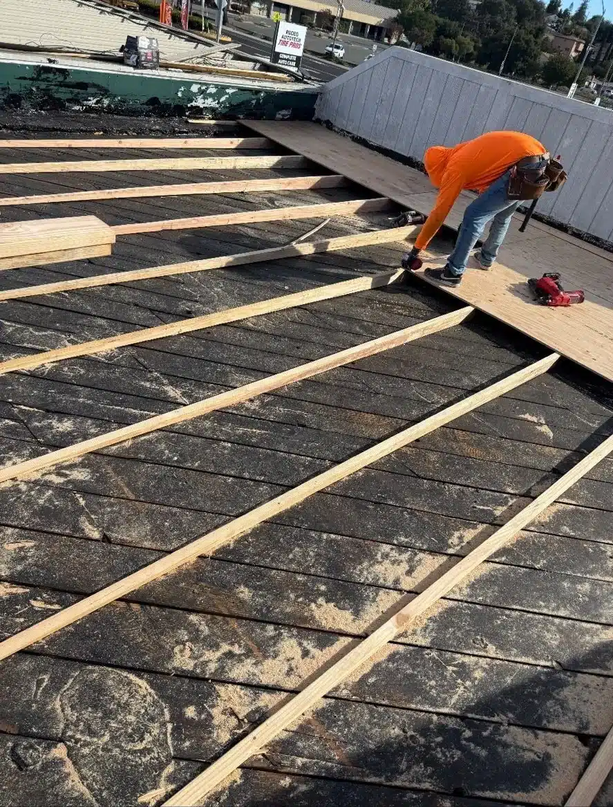 Roofer installing new boards over the old plank deck during a commercial reroof in Rodeo CA