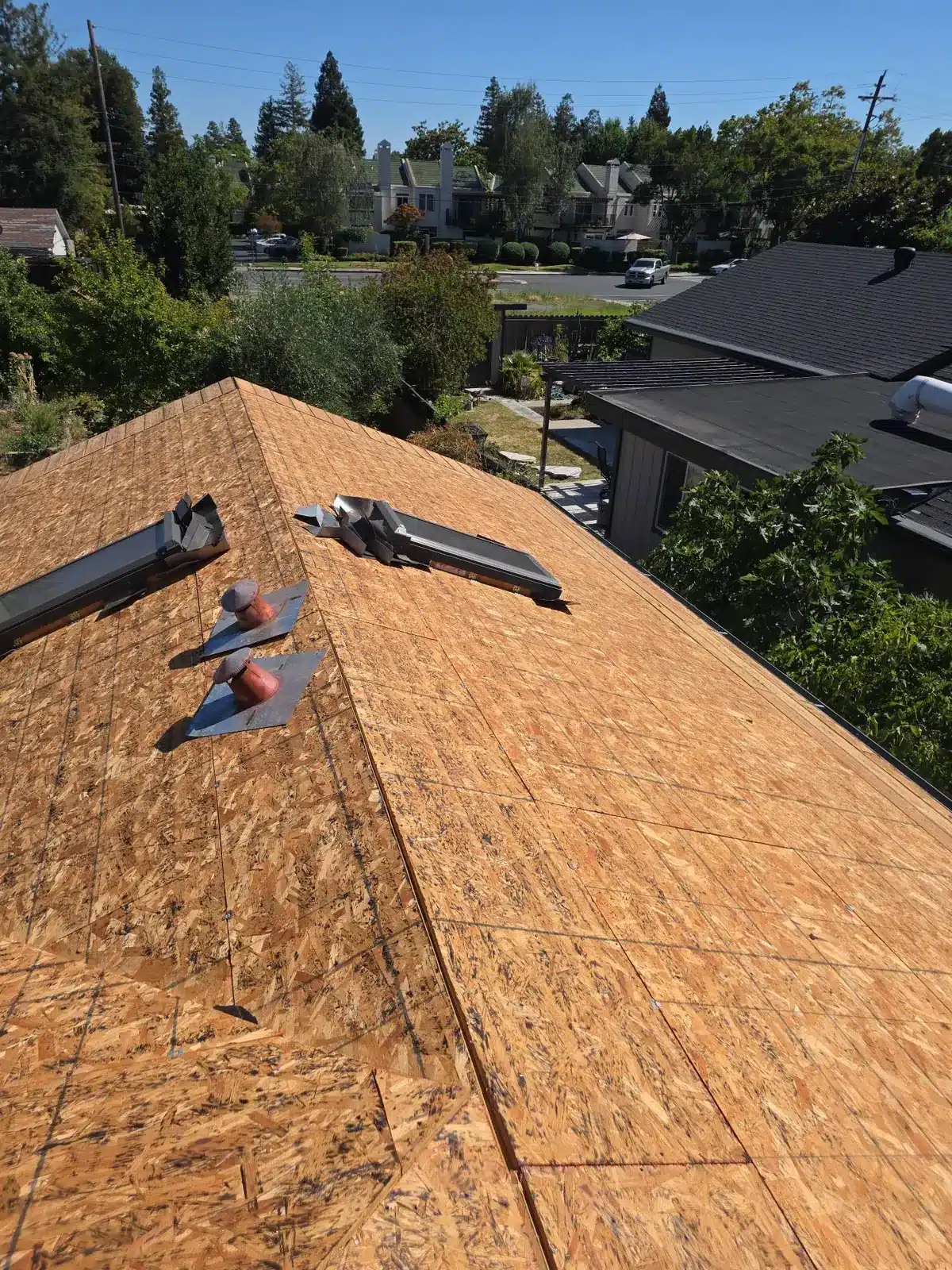 New OSB sheathing over the existing roof deck with new pipe flashings and ridge vent parts in Pleasant Hill