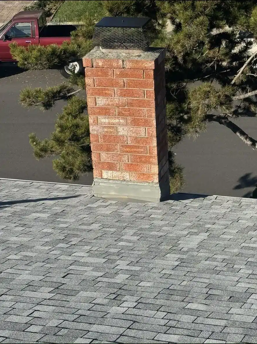 Brick chimney with a new spark arrestor cap on the finished San Jose shingle roof