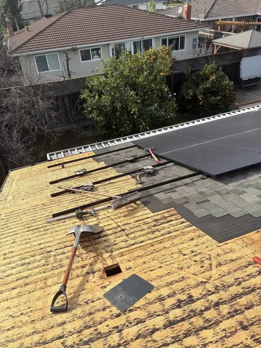 Roof section stripped to the plywood deck during roof repair under solar panels in San Jose